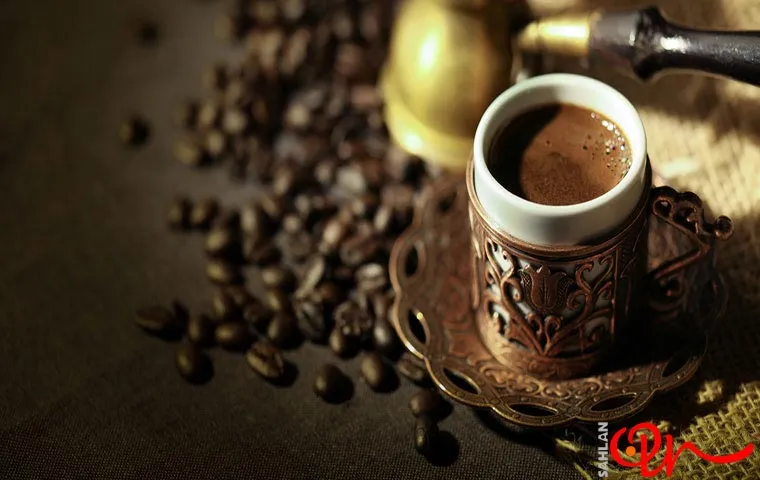 یک لیوان قهوه آماده در کنار دانه های قهوه