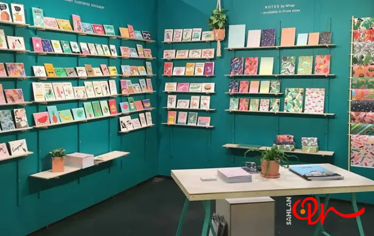نمایشگاه نوشت افزار با دیوارهای سبز و قفسه‌های چوبی