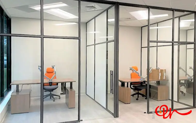 پارتیشن شیشه‌ای مشهد با قاب طوسی رنگ و میز قهوه‌ای و صندلی نارنحی