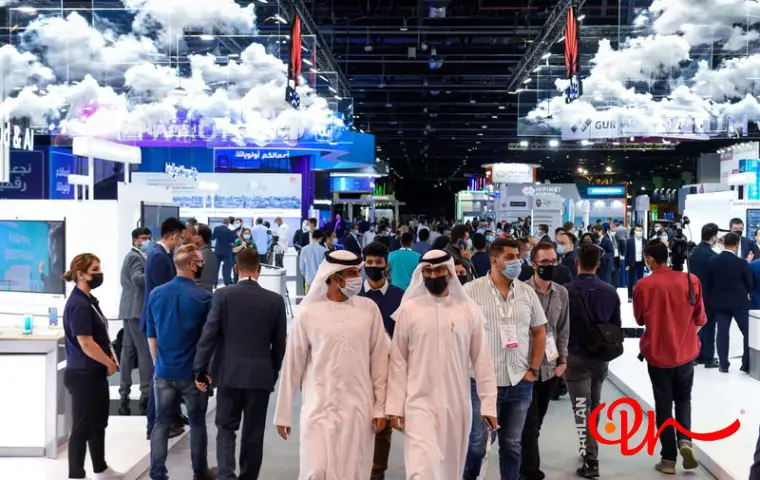 فضای داخلی نمایشگاه و مخاطبان در حال رفت و آمد با لباس عربی و ماسک