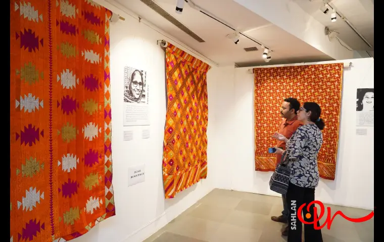 چند نمونه پارچه در نمایشگاه نساجی اصفهان و خانم و آقایی در حال تماشای آن